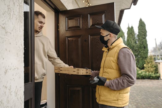 Courier delivering pizza boxes at the doorstep using contactless payment method.