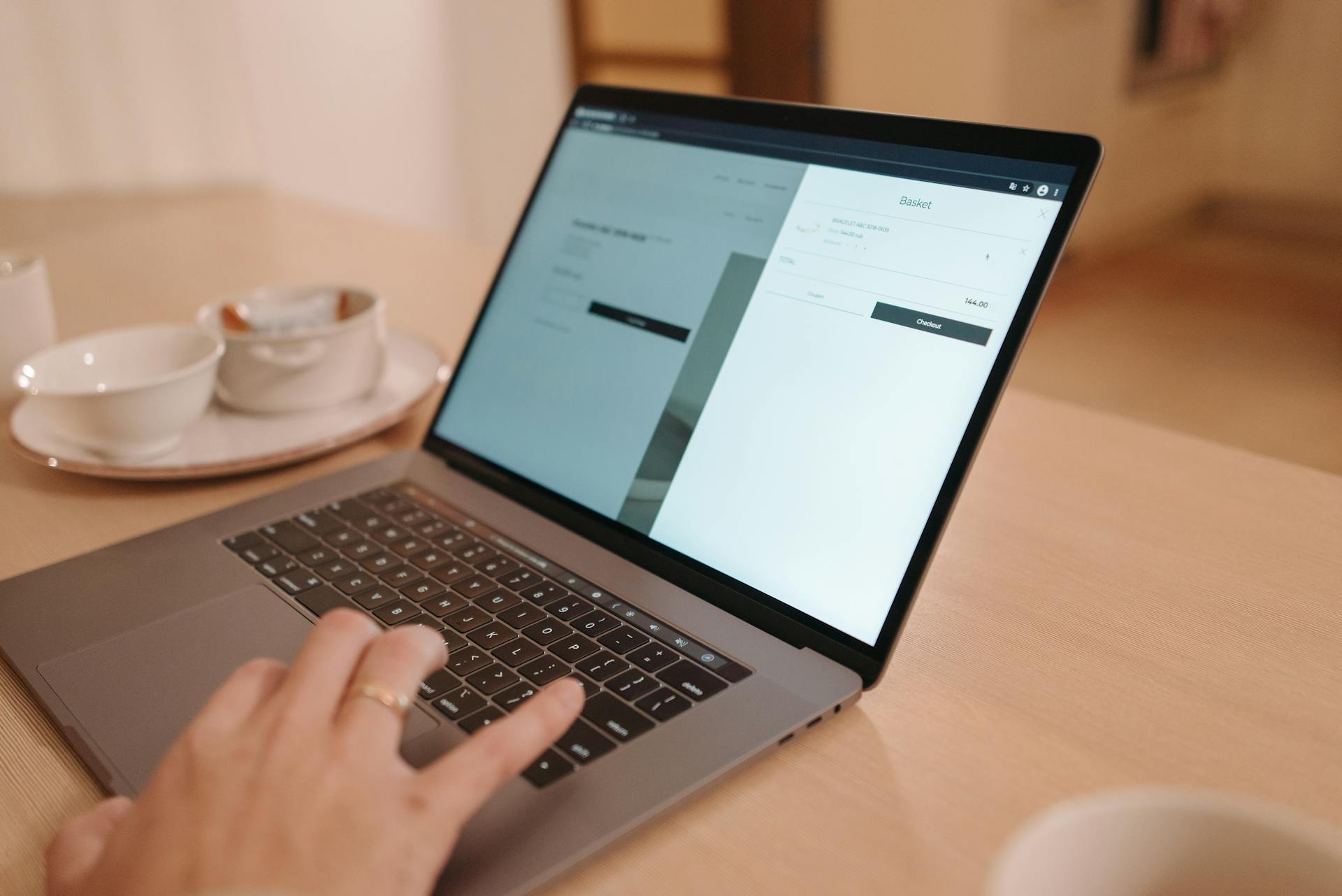 Close-Up Shot of a Person Using a Laptop on Wooden Surface