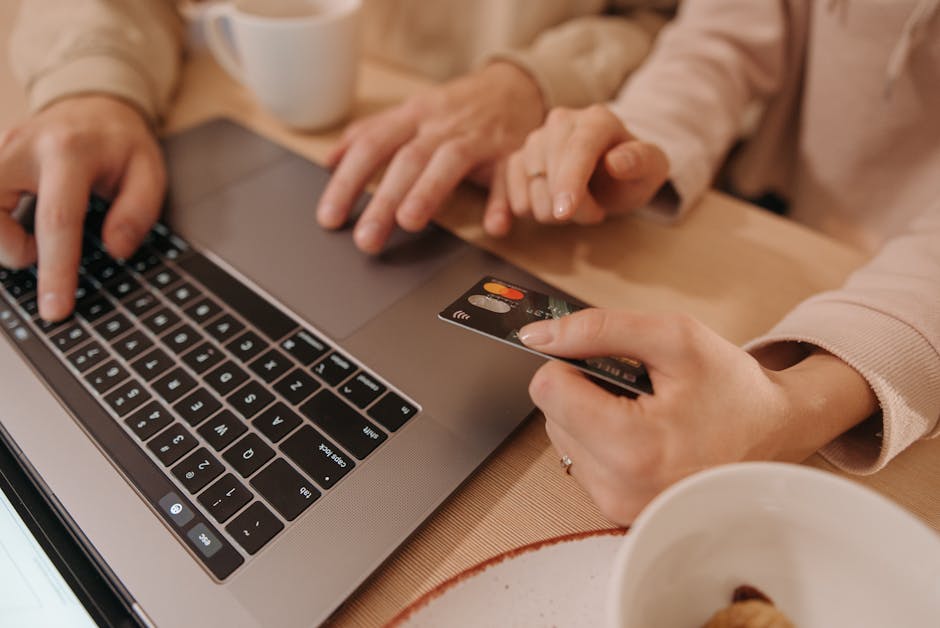Close-up of hands using a laptop and credit card for an online payment or shopping transaction.