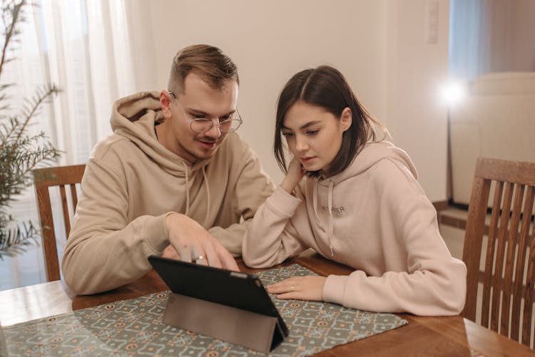 Man And Woman Looking At The Screen Of A Tablet