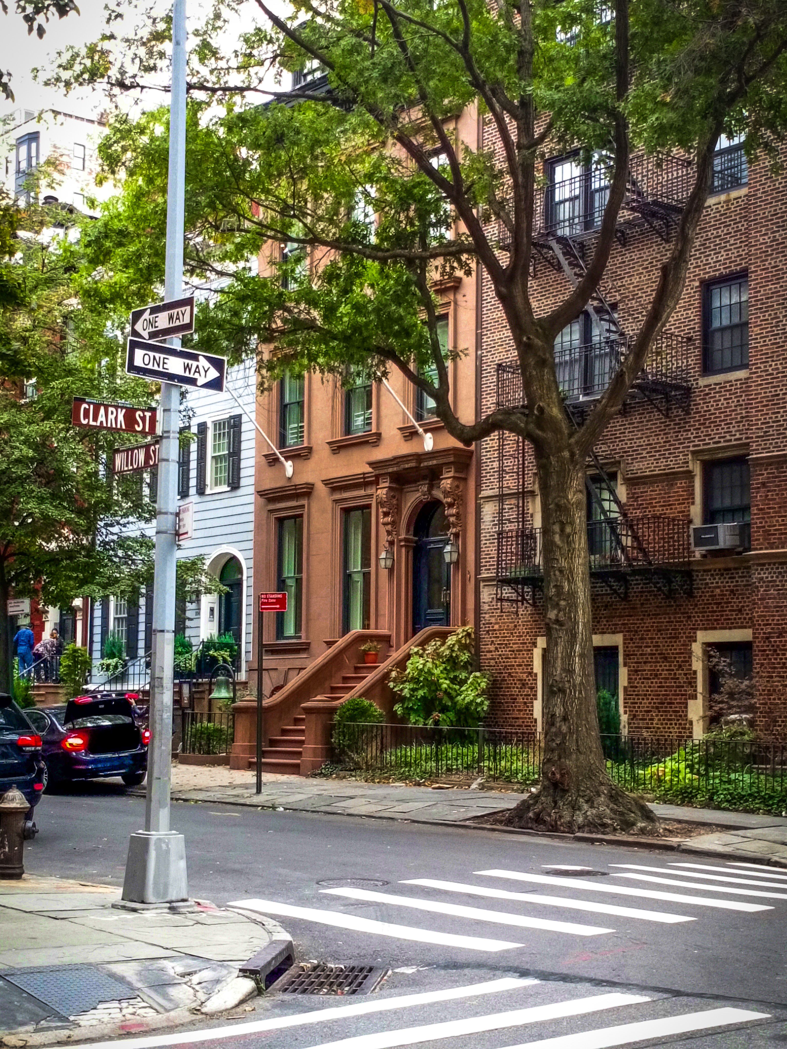 Lively Brooklyn street scene featuring historic buildings, trees, and iconic brownstones on Clark Street.