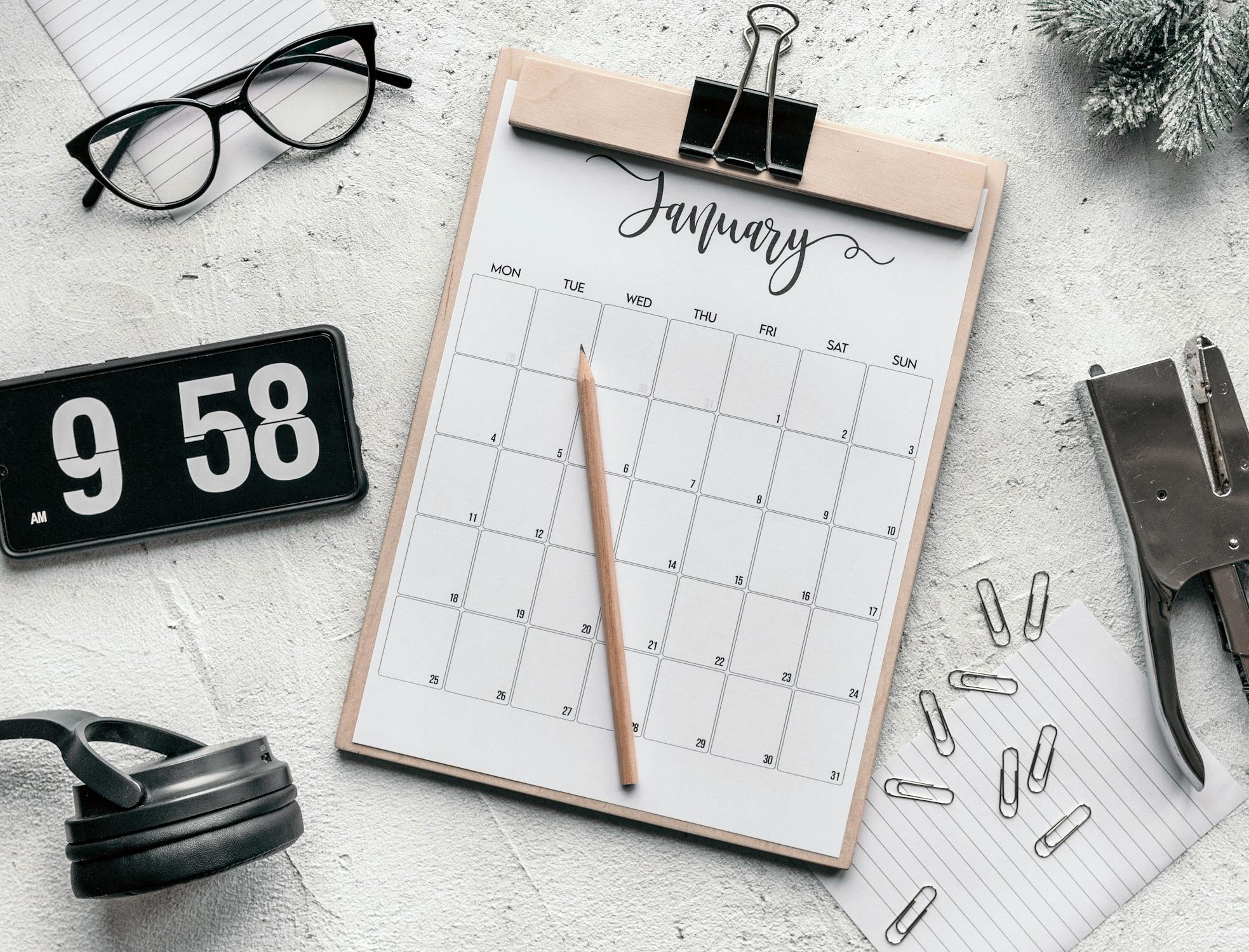 Clipboard with calendar placed on desk amidst stationery · Free Stock Photo