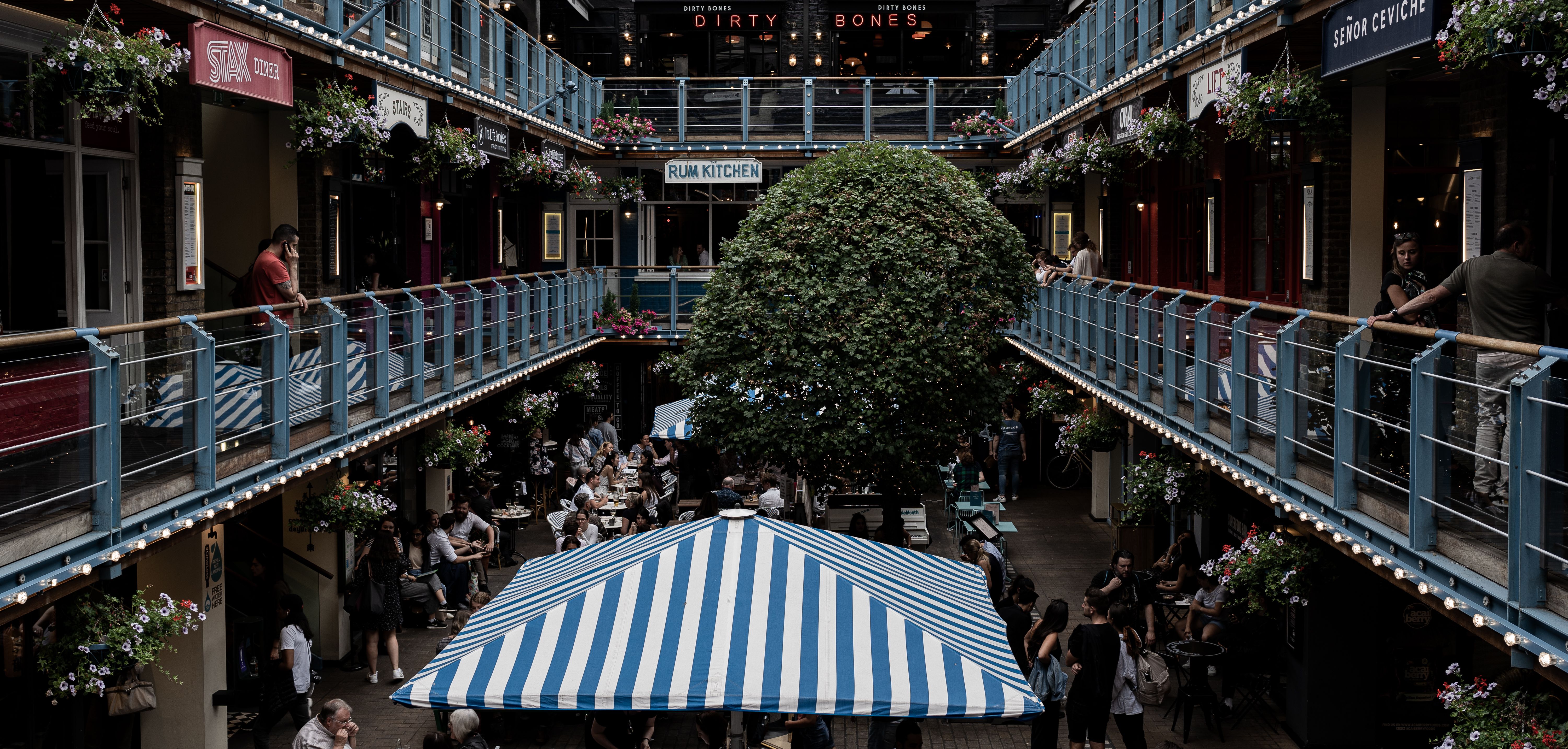 Bustling courtyard with multiple restaurants and diners enjoying a cozy atmosphere in London.