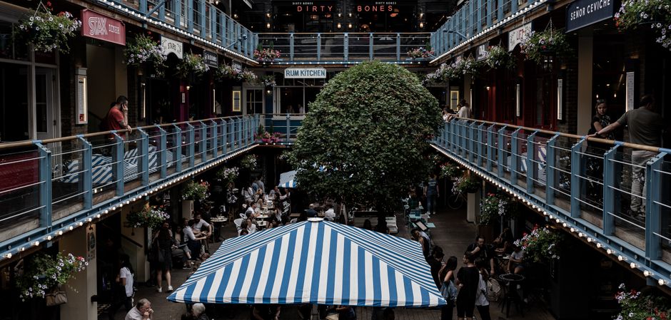 Bustling courtyard with multiple restaurants and diners enjoying a cozy atmosphere in London.