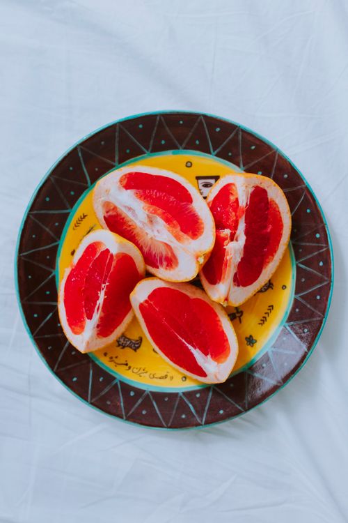Free Juicy grapefruit slices on a colorful decorative plate. Perfect for healthy lifestyle concepts. Stock Photo