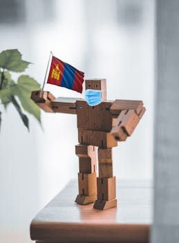 A wooden robot holding a Mongolian flag and wearing a face mask, symbolizing protection and new normality.