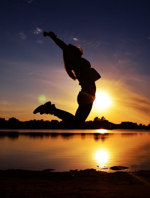 Woman Jumping Near Body of Water