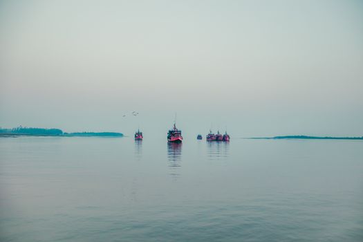 Picturesque view of yachts sailing on surface of calm water of ocean on cloudy day