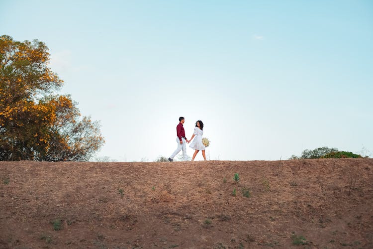 Couple Holding Hands Walking On The Hill