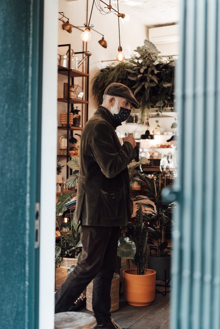 Senior Man Entering Shop With Potted Plants