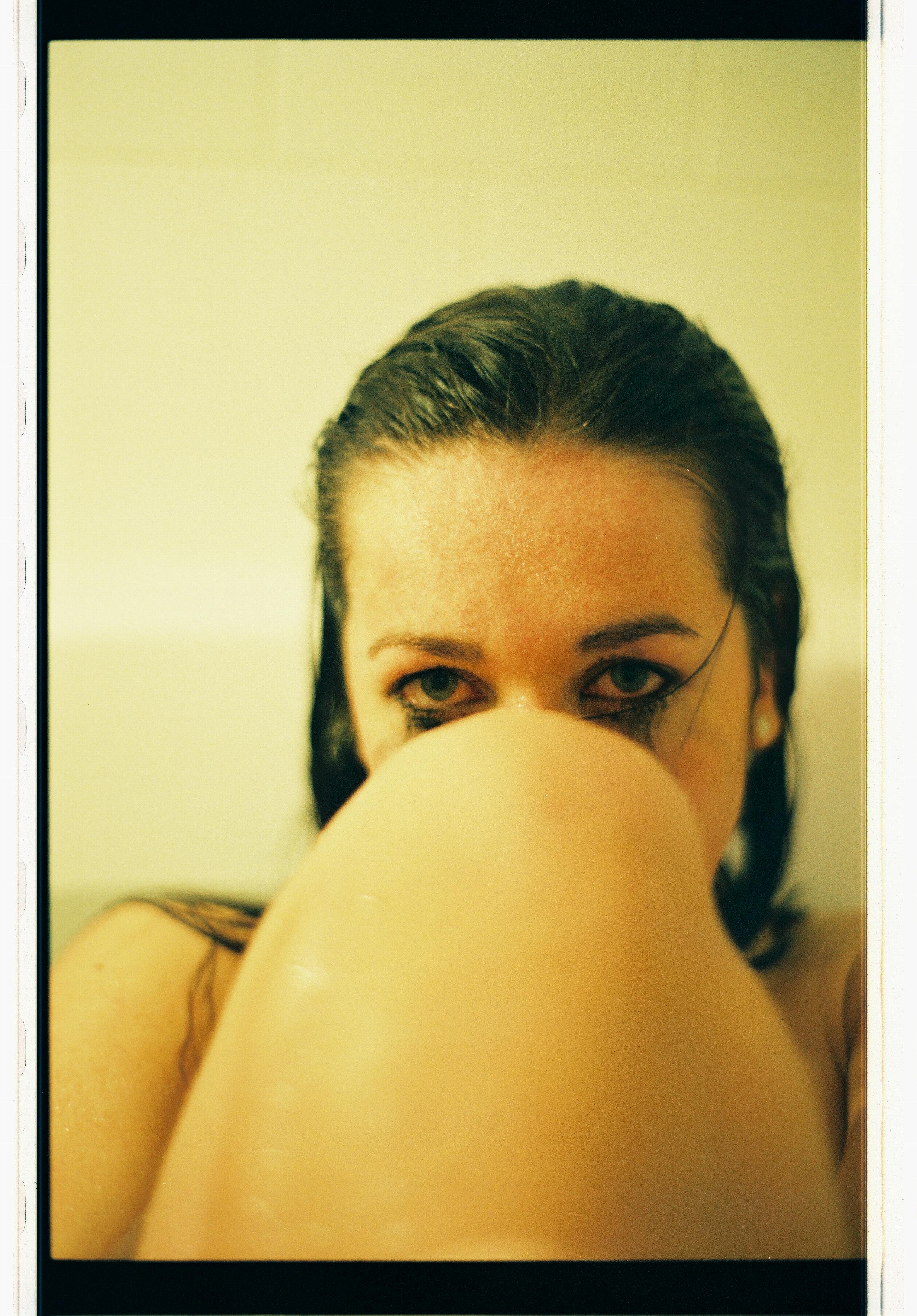 Artistic close-up portrait of woman in bathtub with wet hair.