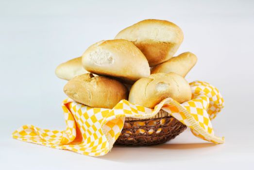 A stack of fresh buns in a wicker basket with a yellow checkered cloth on a white background. Perfect for food photography.