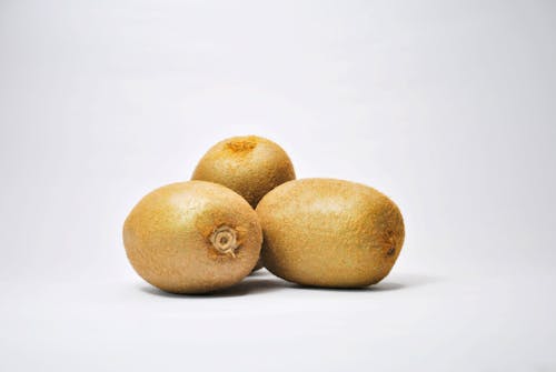 Free Brown Round Kiwi Fruits on White Surface Stock Photo