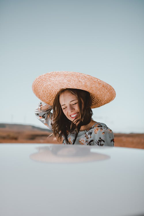 Free Cheerful young lady smiling near car while standing on field during trip Stock Photo