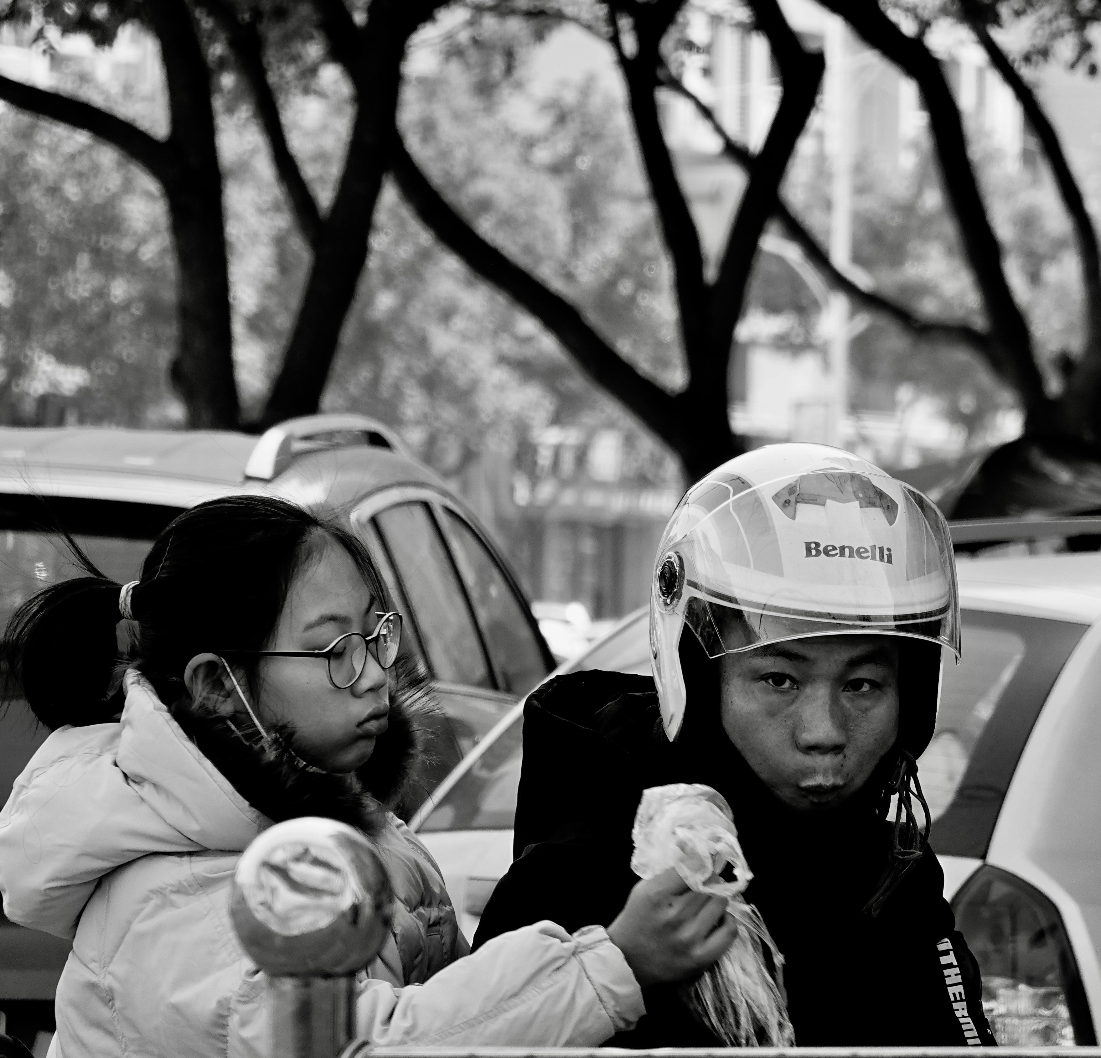 Black and white photo capturing an urban scene in Wenzhou with a couple on a motorcycle.