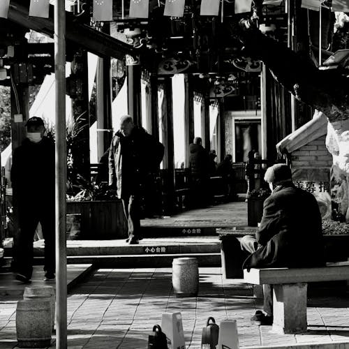 Фотография людей, сидящих на скамейке в оттенках серого