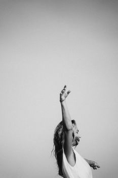 An artistic black and white portrait of a woman joyfully raising her arms, expressing freedom.