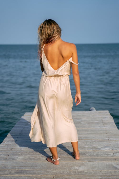 A Woman Wearing a White Dress on a Pier