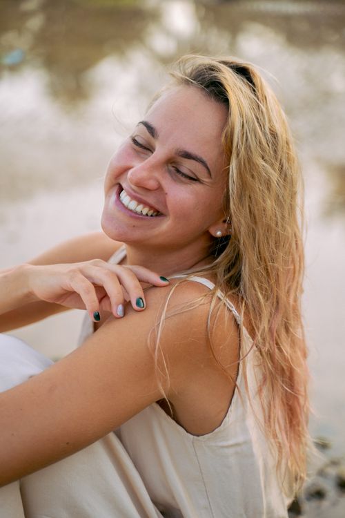 Free Joyful woman with closed eyes smiling by a serene lakeside, exuding a sense of peace. Stock Photo