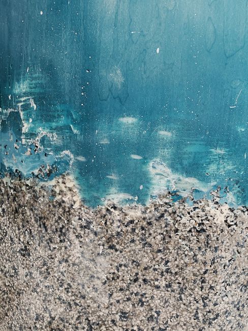 Close-up of a textured blue wall with peeling paint creating a rough pattern.