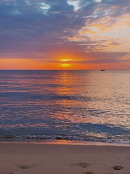 A tranquil sunset over Phú Quốc Island, reflecting vivid hues on calm seas and sandy shores.