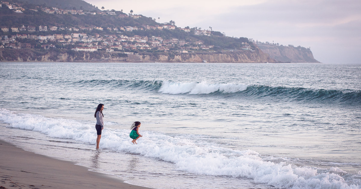 Mother and daughter joyfully playing by the waves at Redondo Beach, California.