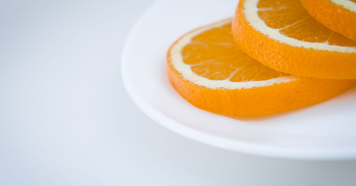 almonds and orange slices on a clean white plate with morning sunlight