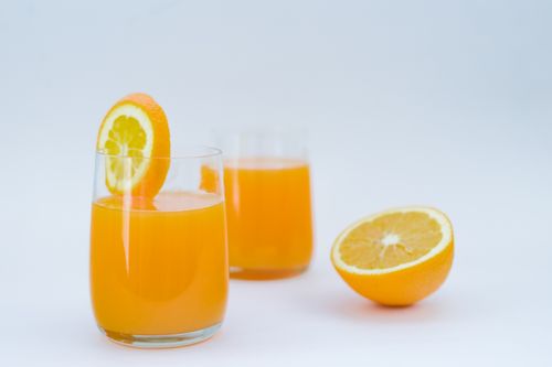 Free Refreshing glass of freshly squeezed orange juice with citrus slices in a studio setting. Stock Photo