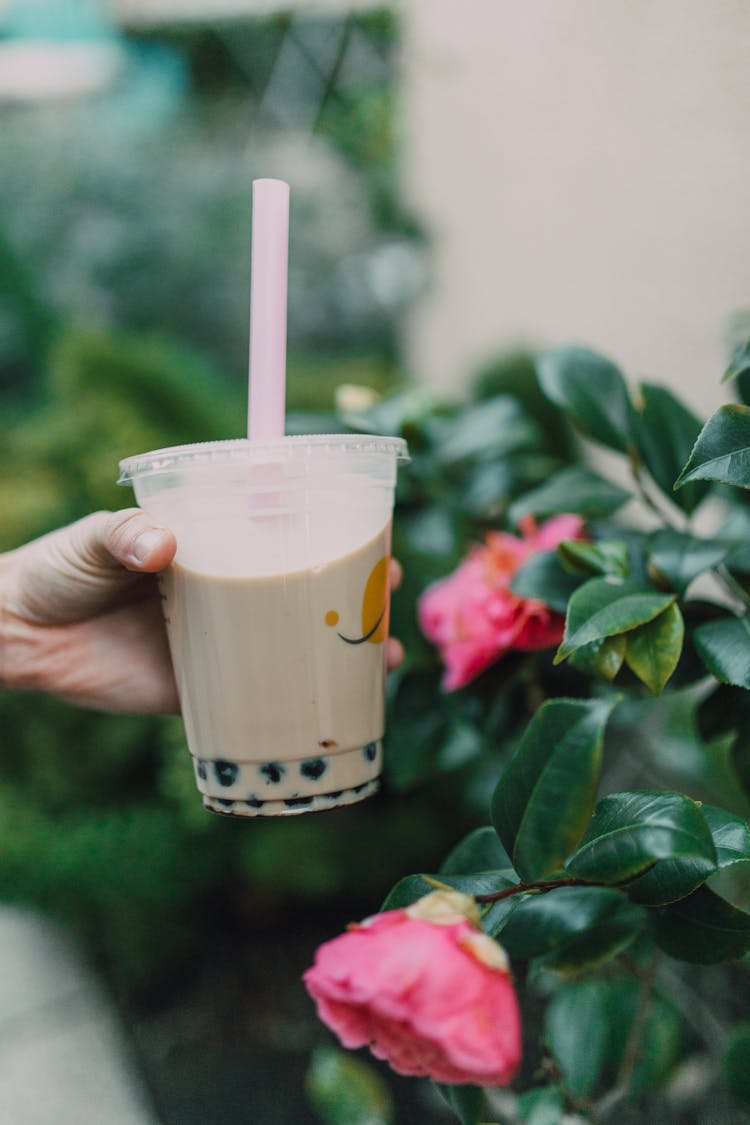 A Hand Holding A Plastic Cup With Milk Tea