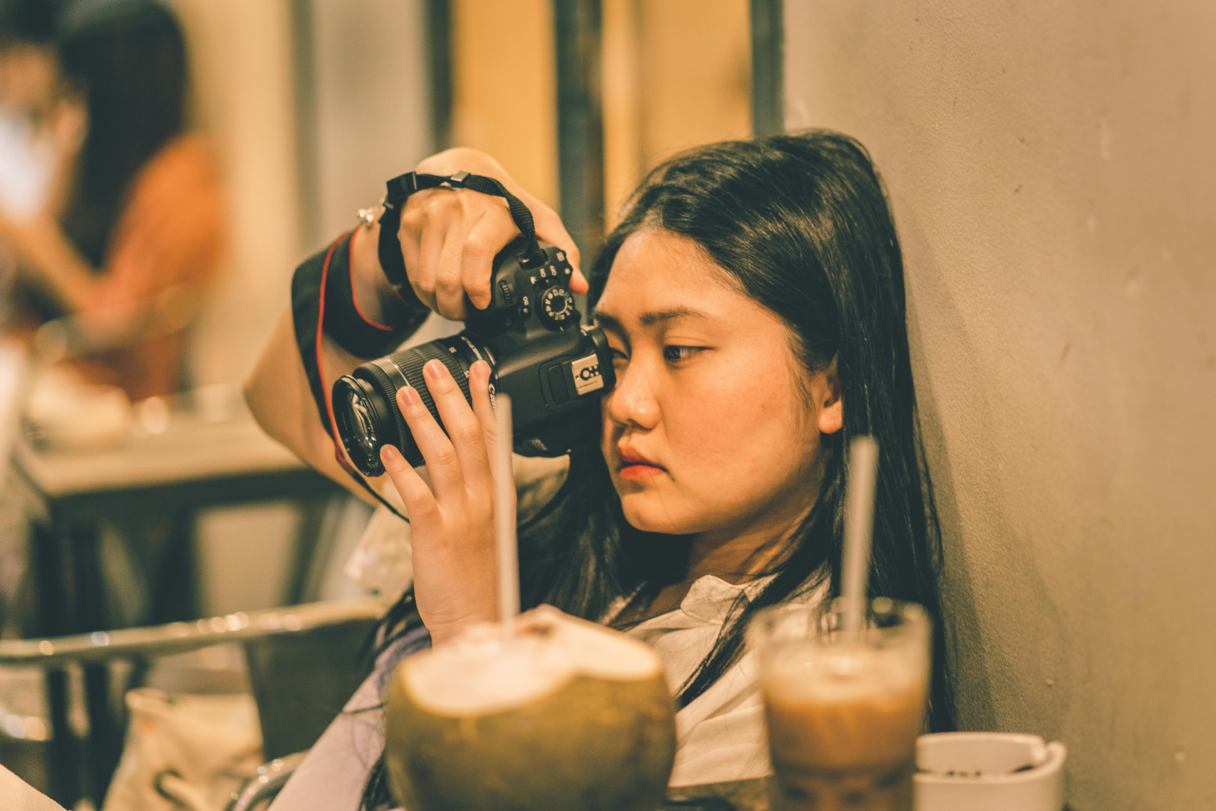 a woman holding a black dslr camera