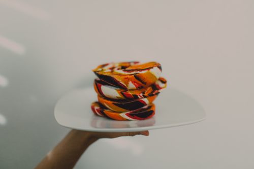 Free Stacked vibrant bagels on a plate held up, captured in soft lighting, ideal for food enthusiasts. Stock Photo