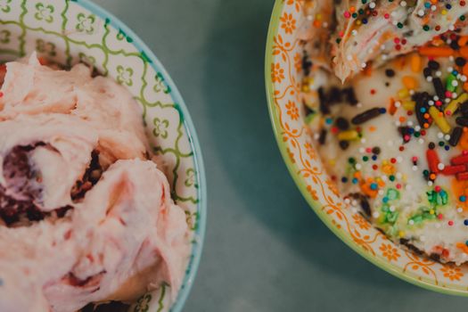 Close-up of colorful ice cream with sprinkles in ceramic bowls, top view.
