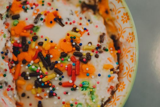 Close-up of vibrant ice cream topped with colorful sprinkles in a decorative bowl.