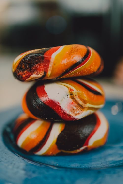 Free A trio of vibrantly colored bagels captures attention with artistic swirls, perfect for food photography enthusiasts. Stock Photo