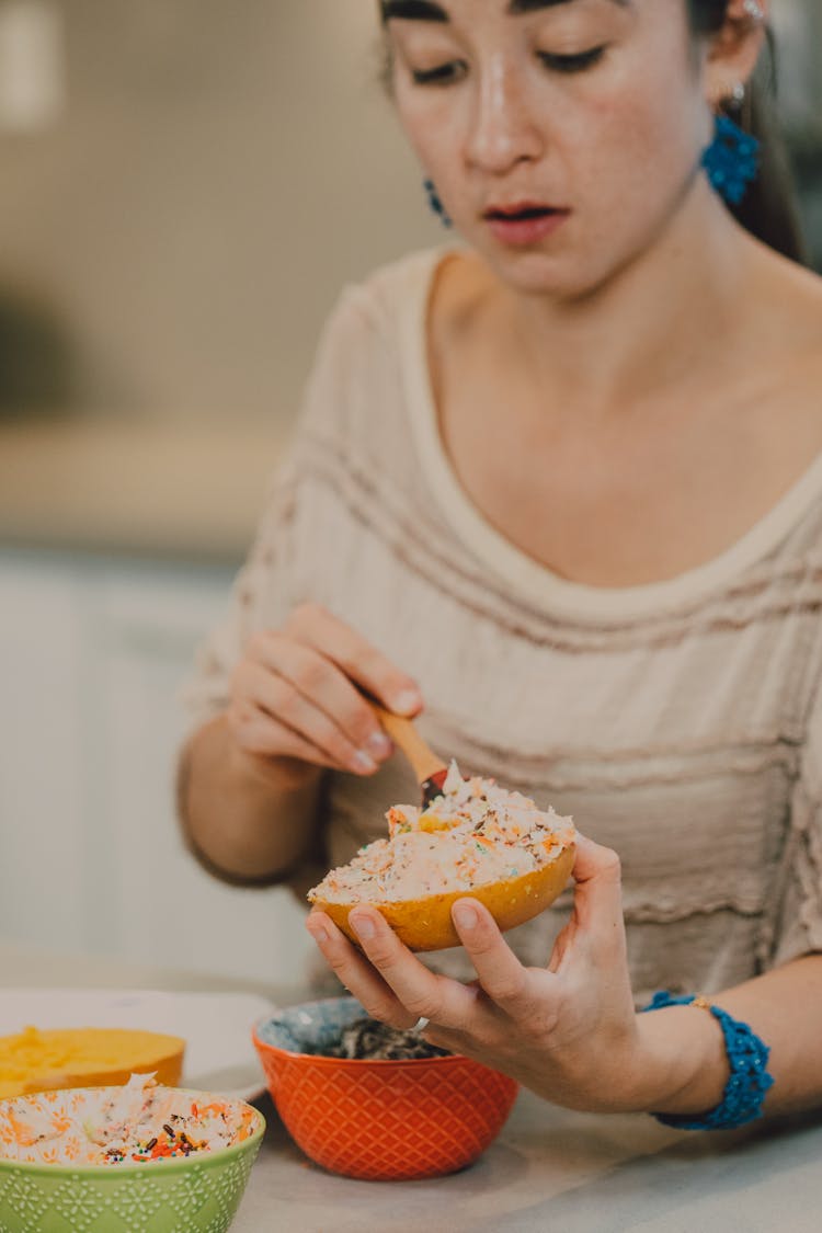 
A Woman Applying Spread On A Bagel