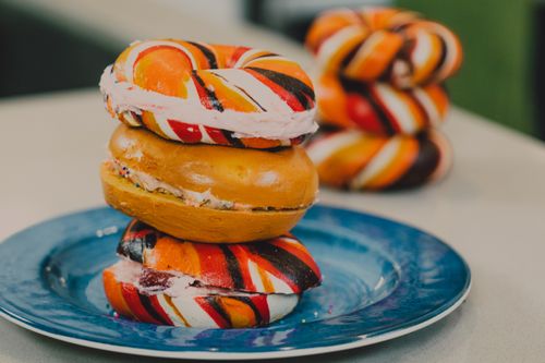 Free Close-up of vibrant rainbow bagels with creamy filling, stacked on a plate. Stock Photo