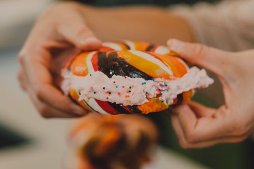 Free Vibrant rainbow bagel filled with cream cheese and sprinkles, offering a sweet and indulgent treat. Stock Photo
