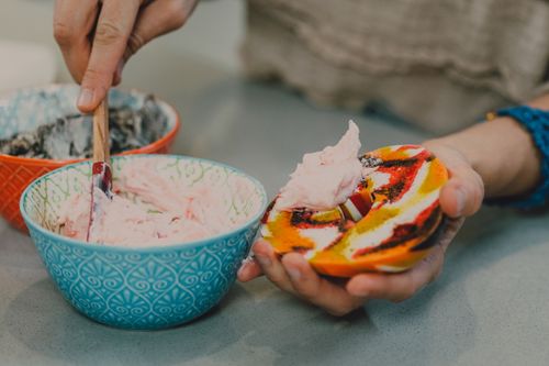 Free A vibrant bagel with cream cheese being prepared, highlighting a delicious snack option. Stock Photo