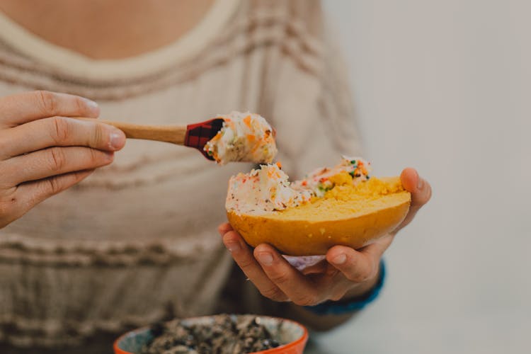 A Person Applying Spread On A Bagel