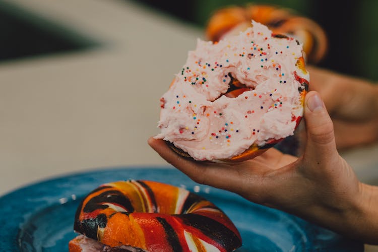 

A Person Holding A Bagel With Spread