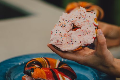 Free Colorful bagel smeared with pink cream cheese and sprinkles for a fun snack. Stock Photo