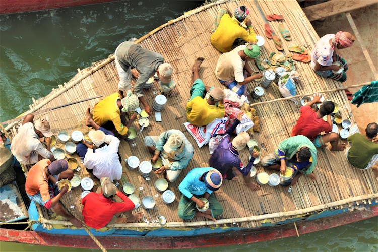 People Sitting On Brown Wooden Boat Eating Their Lunch