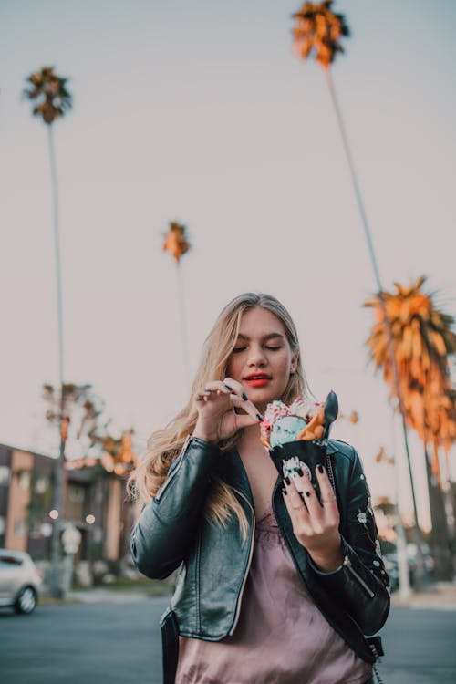 Free A Woman in a Black Leather Jacket Holding an Ice Cream Stock Photo