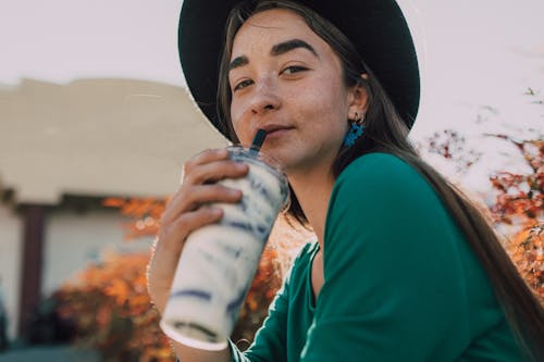 Pretty Woman Looking at Camera while Holding a Beverage
