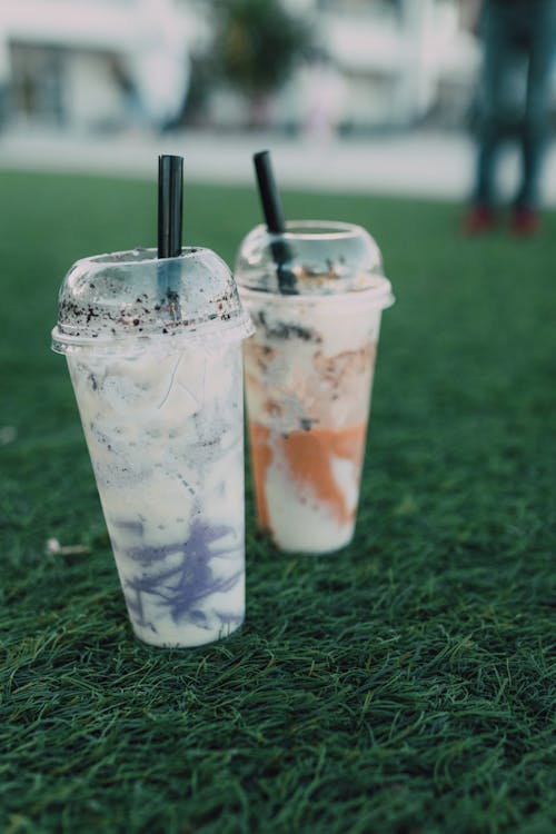 Disposable Plastic Cups of Milkshake on Green Grass