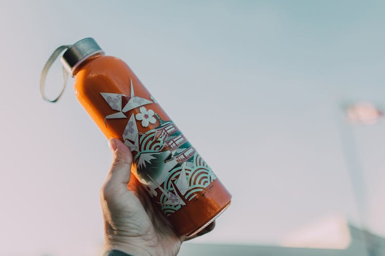 A Person Holding A Water Bottle With Artwork