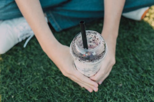 Person Holding Clear Glass Cup With Black Straw