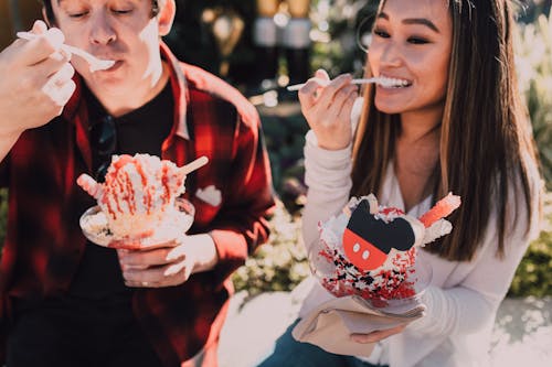 Woman in White and Red Floral Long Sleeve Shirt Holding Ice Cream Cone