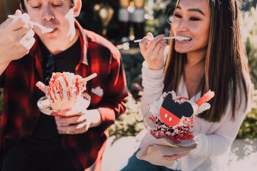 Free A couple delighting in colorful, festive ice cream treats outdoors on a sunny day. Stock Photo