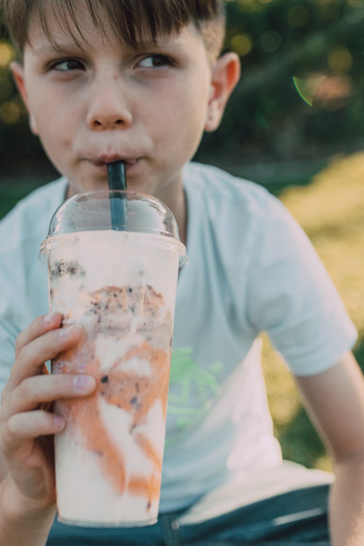 A Young Boy Drinking A Milkshake